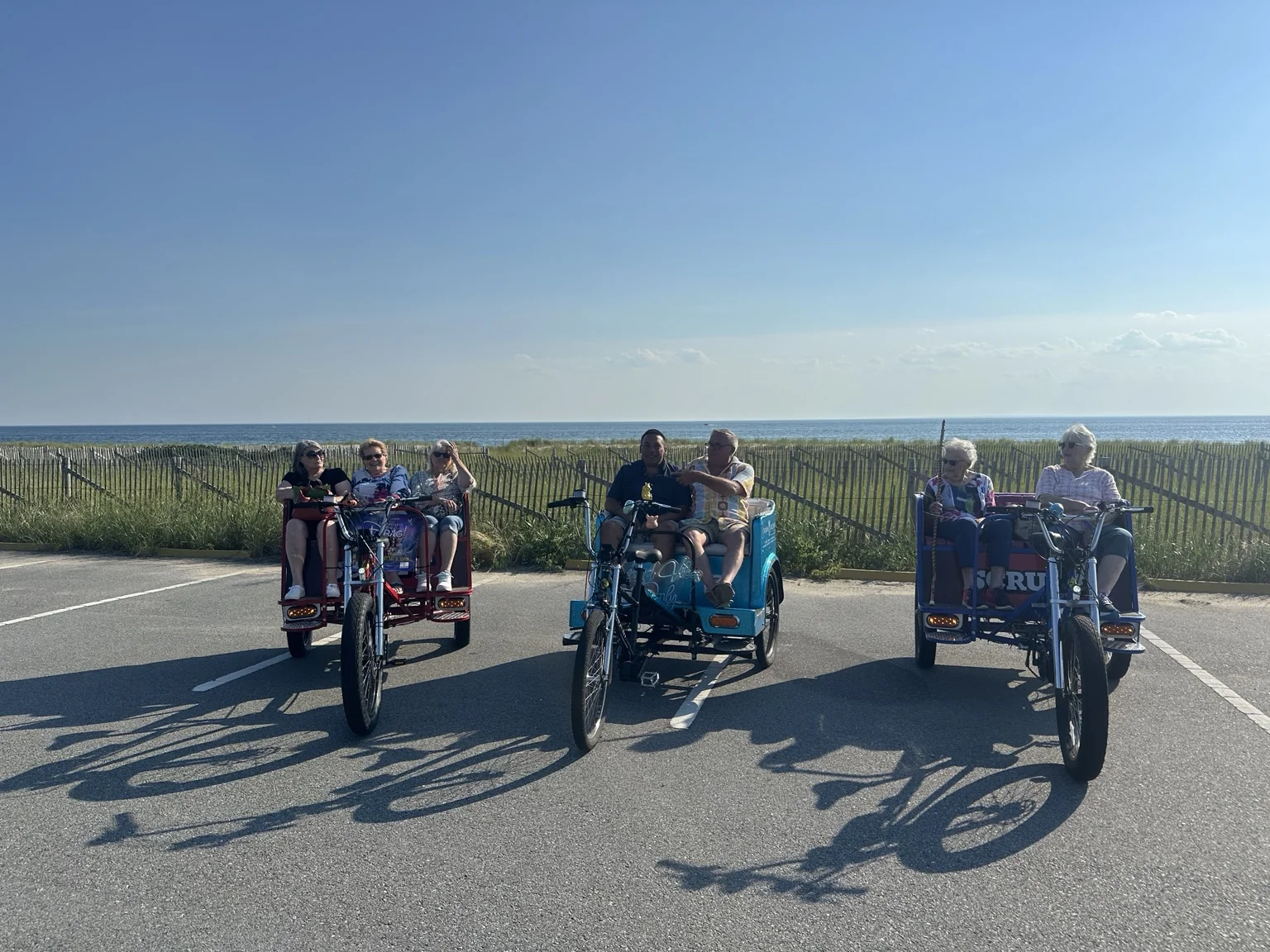 Guests and riders in three pedicabs beside the Provincetown dunes.