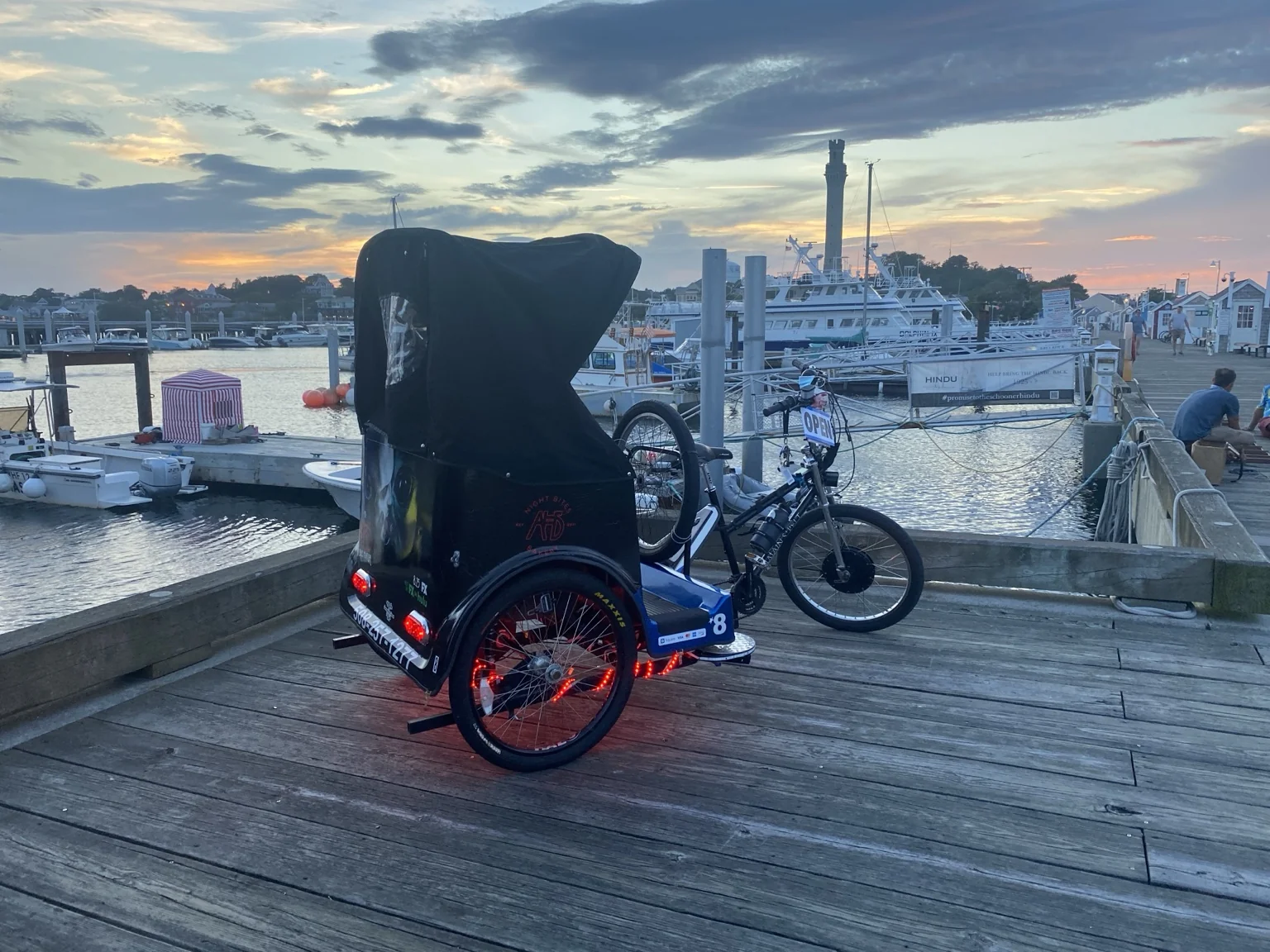 A covered pedicab at the Provincetown waterfront at sunset.